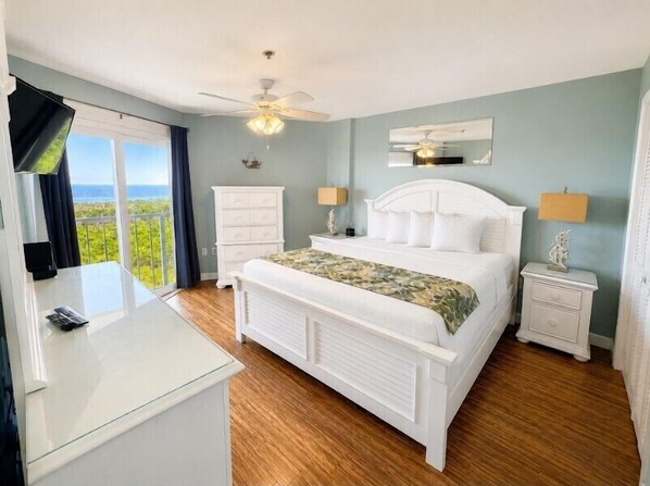 A bedroom with a bed, bedside tables, a desk, and a view of the outdoors.