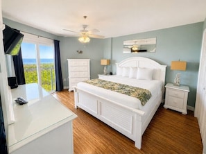 A bedroom with a bed, bedside tables, a desk, and a view of the outdoors.