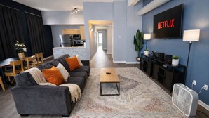 A modern living room with a grey sofa, a coffee table, and a TV displaying 'NETFLIX'. - Spacious Dwntwn Loft Playhouse SQ, CSU, Clinic (Cleveland)