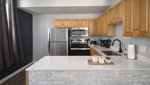 A modern kitchen with wooden cabinets, stainless steel appliances, and a marble countertop. - Spacious Dwntwn Loft Playhouse SQ, CSU, Clinic (Cleveland)