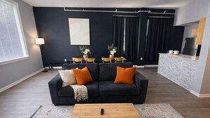 A modern living room with a dark sofa, a coffee table, and a dining area with chairs and a table. - Spacious Dwntwn Loft Playhouse SQ, CSU, Clinic (Cleveland)