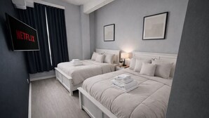 A hotel room with two beds, a TV displaying the Netflix logo, and a framed picture on the wall. - Spacious Dwntwn Loft Playhouse SQ, CSU, Clinic (Cleveland)