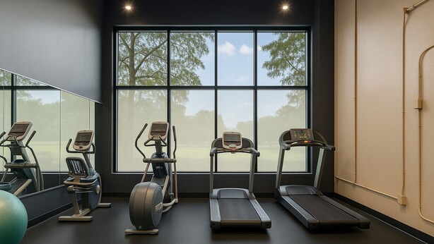 A gym with treadmills, elliptical machines, and a stationary bike, large windows with a view of trees, and a mirror reflecting the equipment. - Spacious Dwntwn Loft Playhouse SQ, CSU, Clinic (Cleveland)