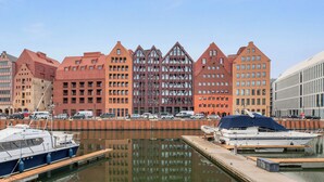 A marina with boats docked, a modern building with a unique architectural design, and a clear sky. - Granaria Jacuzzi Premium Suites by Downtown Apartments (Gdańsk)