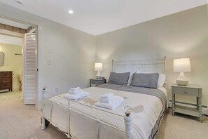 Une chambre à coucher comprenant un lit, deux tables de chevet, une commode, une porte et un luminaire fixé au mur.