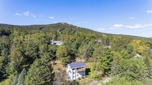 A house surrounded by dense forest with a clear view of the surrounding hills.