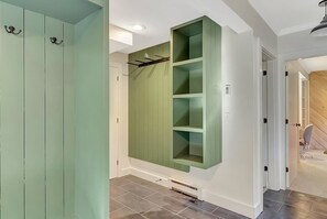A hallway with a green built-in shelving unit, a white door, and a staircase visible in the background.