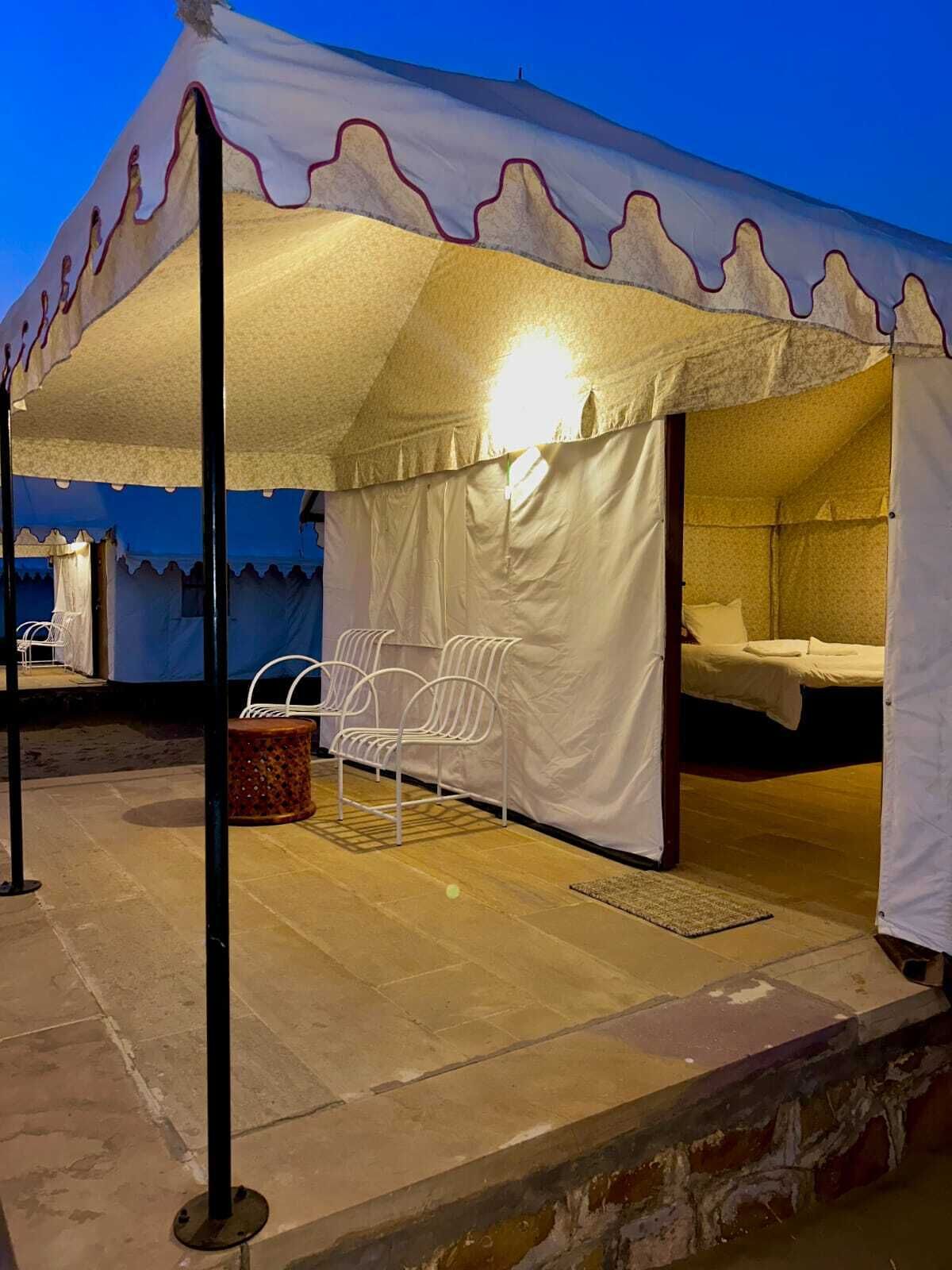 Una carpa con una cama, dos sillas y una mesita.