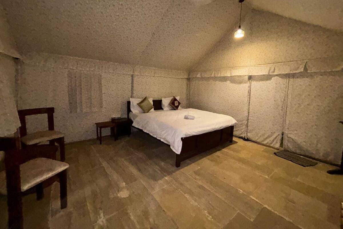 Un dormitorio con una cama de madera, una silla, una mesita de noche y una lámpara colgante.