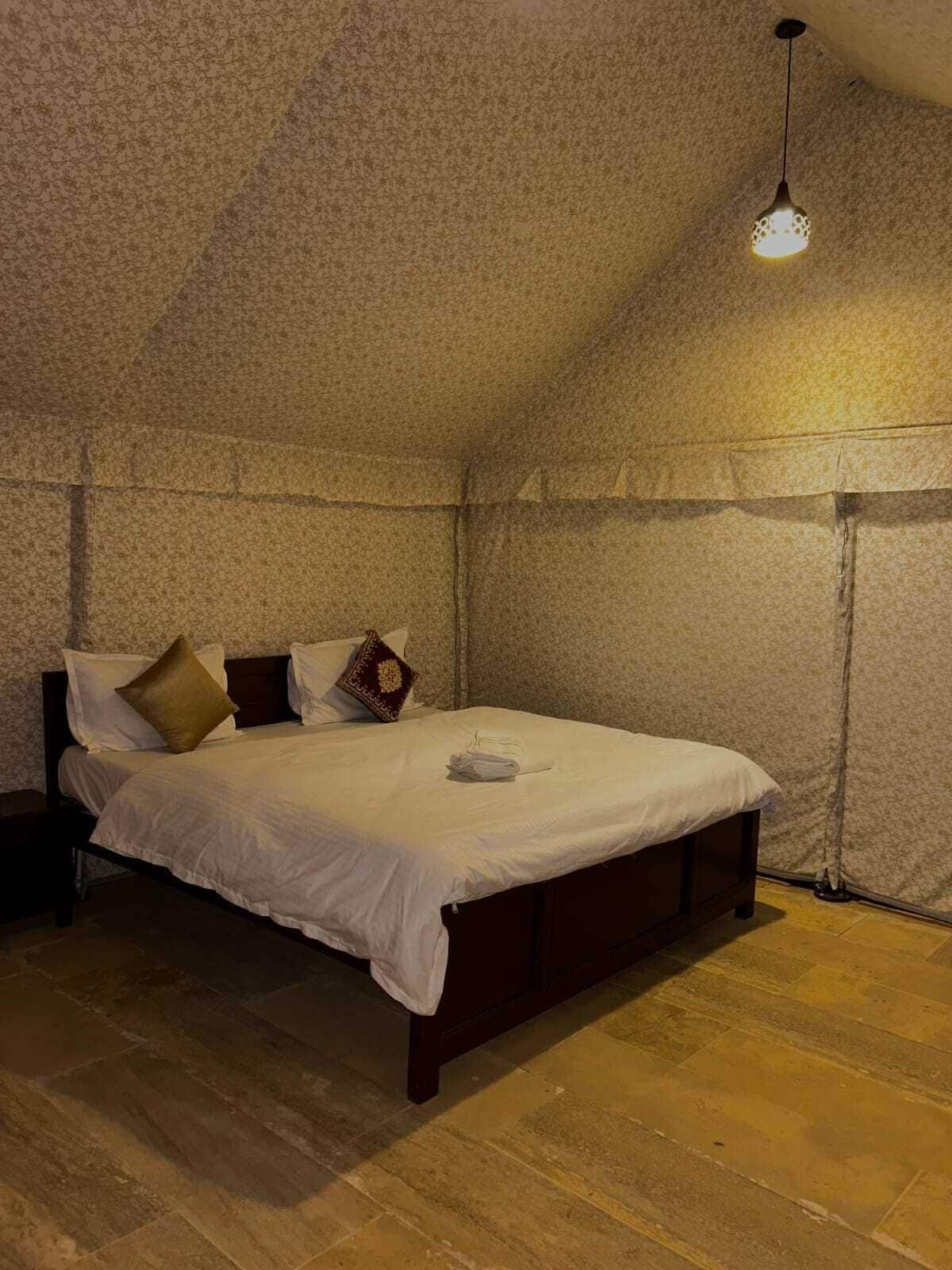 Un dormitorio con una cama individual, una lámpara colgante y una pared con textura.