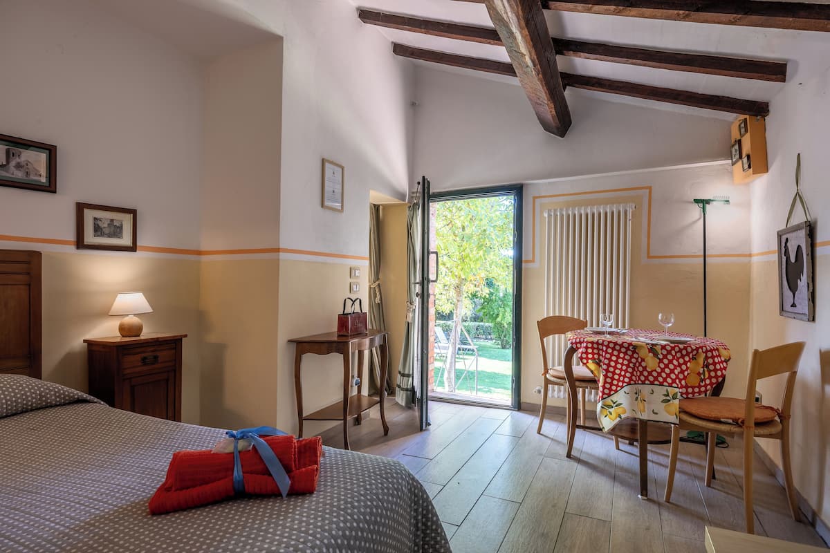 A hotel room with a bed, a table with chairs, a window, and a door leading to an outdoor area.