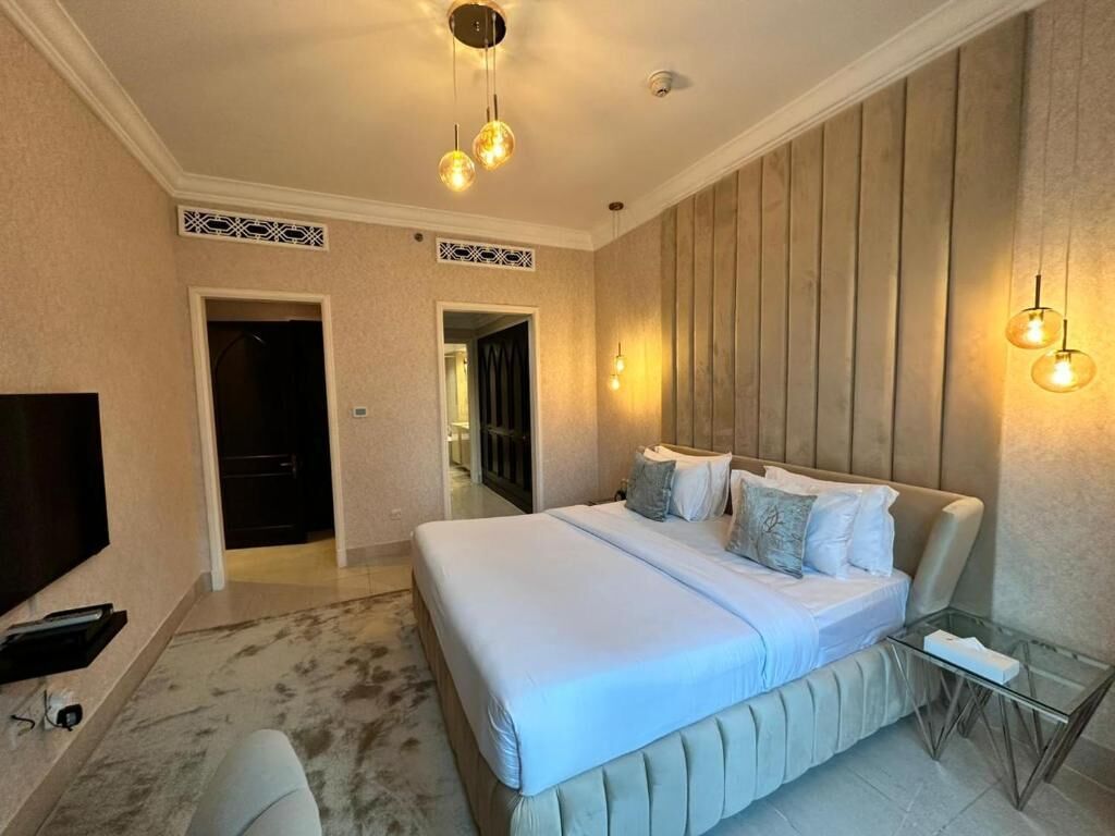 Una habitación de hotel con una cama grande, un televisor y una mesa de vidrio.