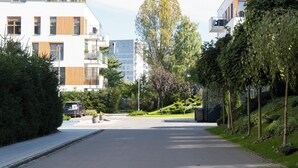 Een moderne woonstraat met eigentijdse gebouwen, een heldere lucht en een verzorgd groen landschap.