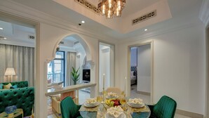 Comedor con una mesa redonda dispuesta para cuatro personas, sillas tapizadas de verde y un centro de mesa decorativo.