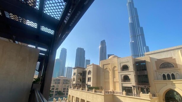 Vista desde un balcón con vistas a un canal, un edificio moderno y el Burj Khalifa al fondo.