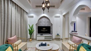 Una sala de estar moderna con televisor, sofá, mesa de centro y elementos decorativos.
