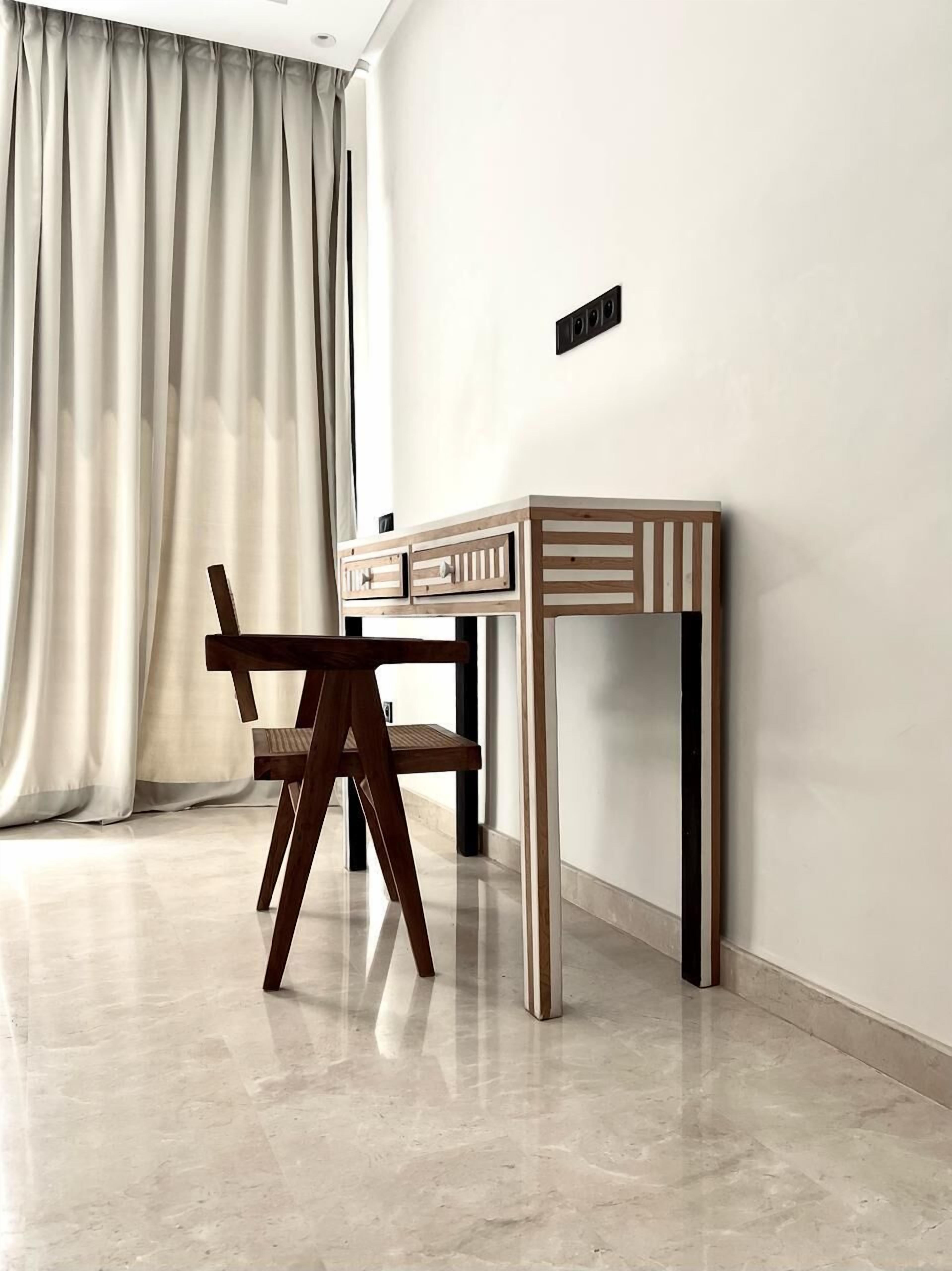 A modern room with a wooden desk, a chair, and a large window with curtains.