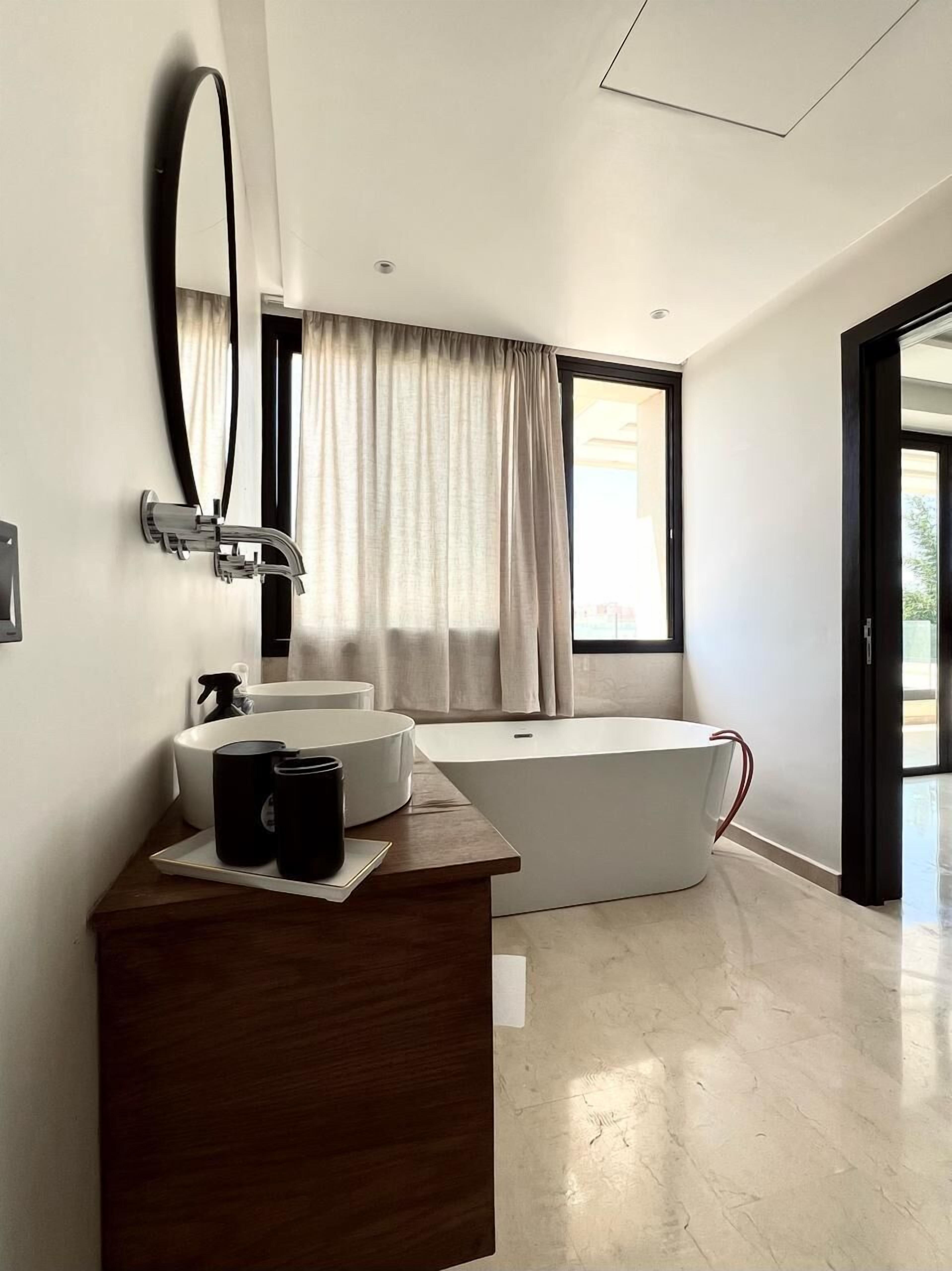 A modern bathroom with a freestanding bathtub, a large mirror, and a wooden vanity.