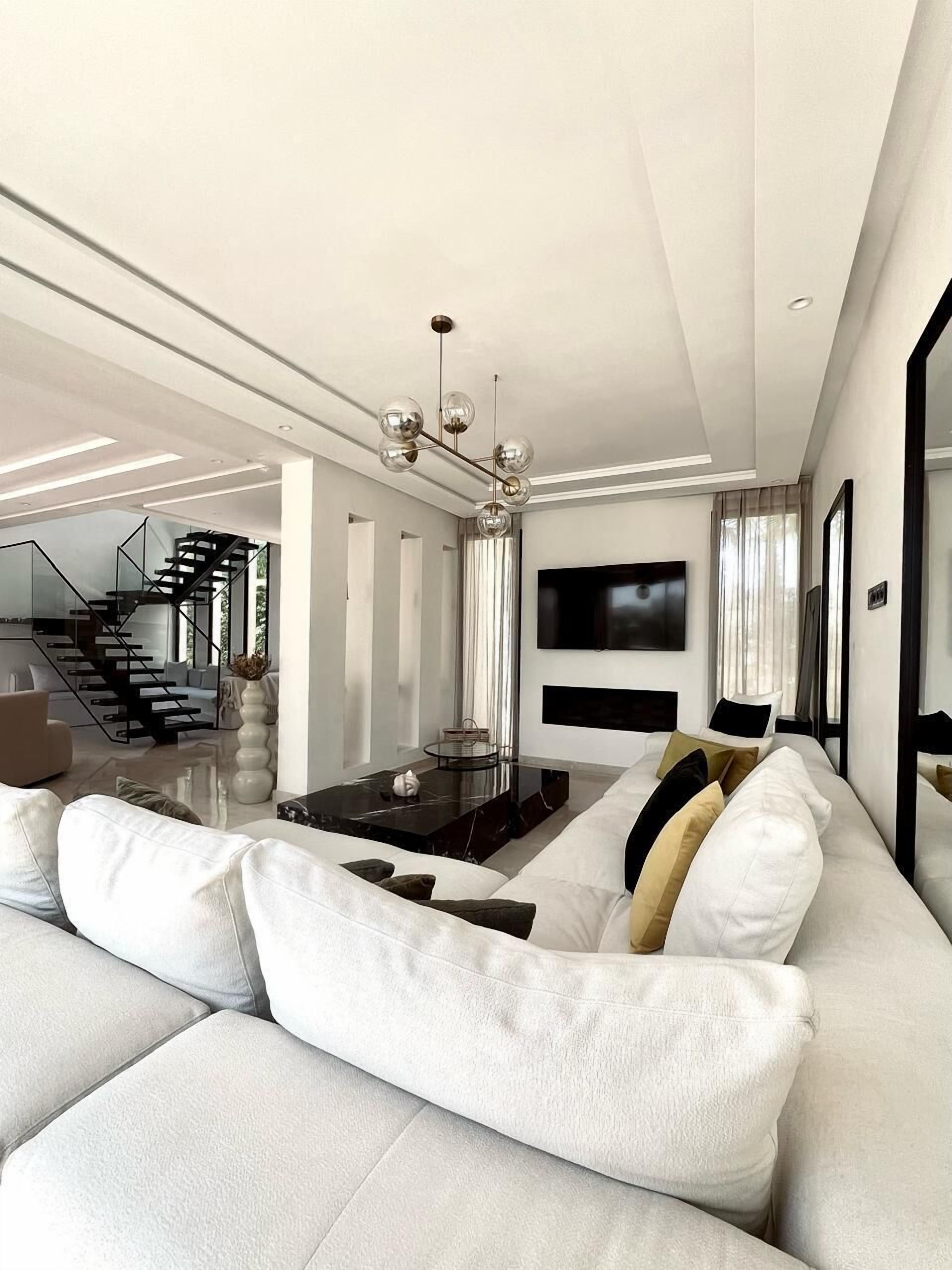Un salon moderne avec un grand canapé, une table basse et un escalier menant à un autre niveau.