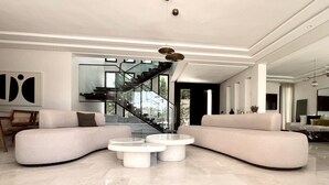 A spacious living room with a large L-shaped sectional sofa, a round coffee table, and a staircase leading to an upper level. - VILLA KECH (Marrakech)