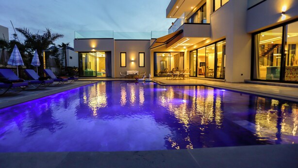 A modern building with a swimming pool, glass doors, and outdoor seating. - VILLA KECH (Marrakech)