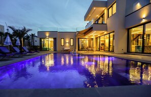 A modern building with a swimming pool, glass doors, and outdoor seating. - VILLA KECH (Marrakech)