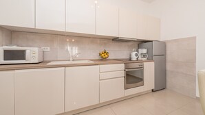 A modern kitchen with white cabinetry, a microwave, a coffee maker, and a refrigerator.