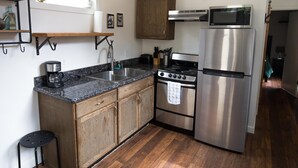 A kitchen with wooden cabinets, a stainless steel refrigerator, a stove, and a microwave.