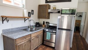Une cuisine dotée de meubles en bois, d’un plan de travail en granit, d’appareils électroménagers en acier inoxydable et d’un parquet.