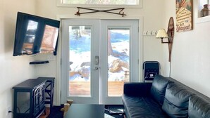 Olohuoneessa on musta nahkasohva, televisio ja suuri ikkuna, josta avautuu näkymä lumiseen maisemaan.