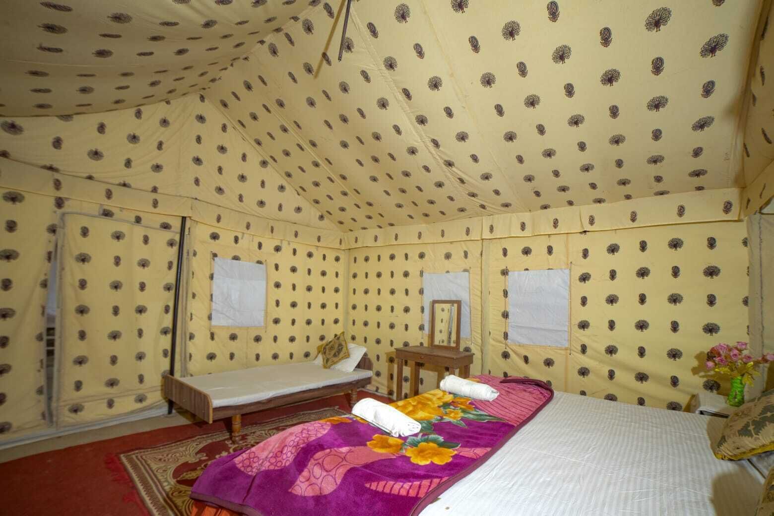Una habitación con carpa, una cama, una mesita y un espejo.