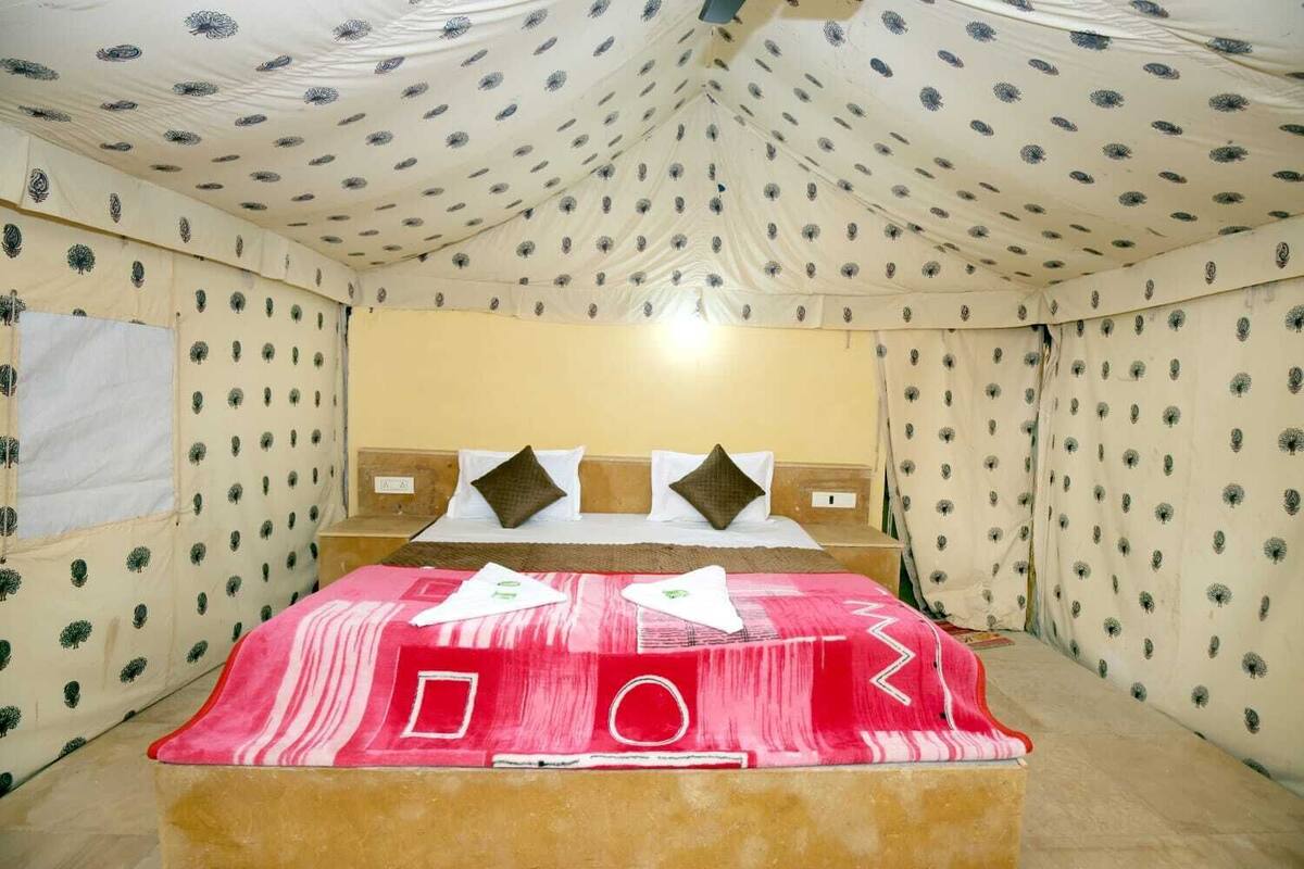 Een kamer met een bed, kussens en een kamerhoge gordijnen.