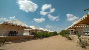 A row of tents with a dirt path between them, under a clear sky. - Royal Gadhvi Desert Camp (Jaisalmer)