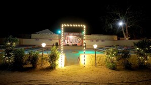 A desert resort with a swimming pool, palm trees, and a marquee. - Royal Gadhvi Desert Camp (Jaisalmer)