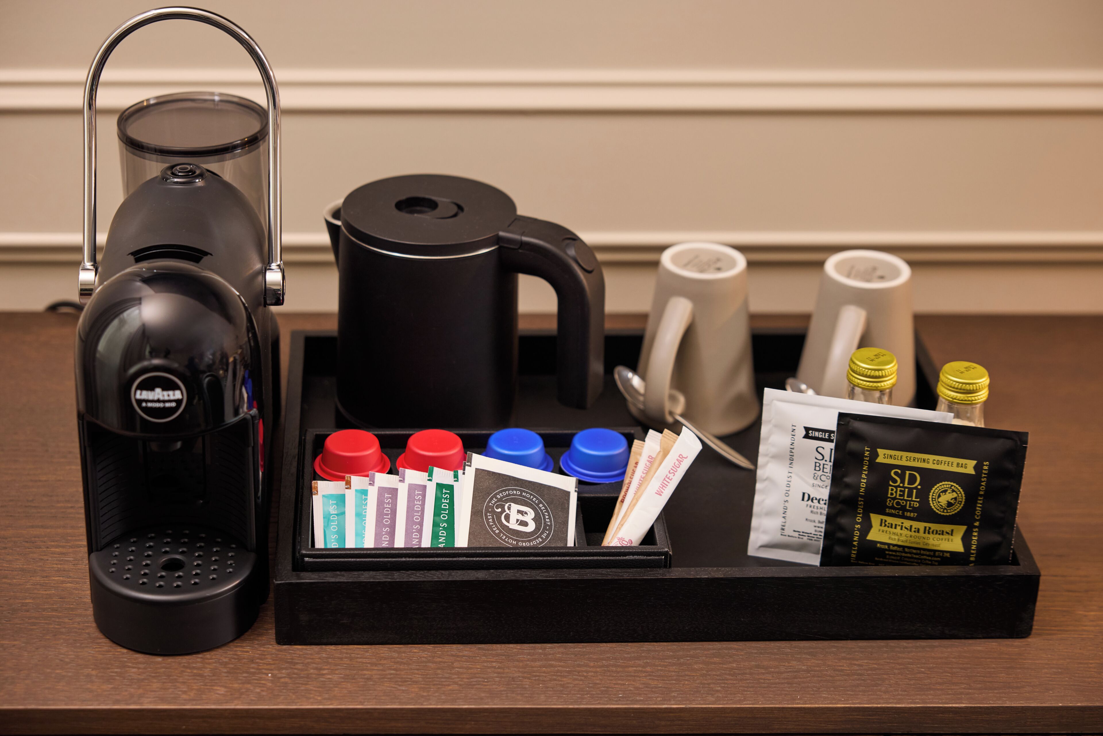 A coffee maker, a kettle, and a tray with coffee pods and a coffee bag.