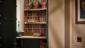 Une bibliothèque remplie de livres et d’objets décoratifs, un vase vert et un tableau encadré accroché au mur.