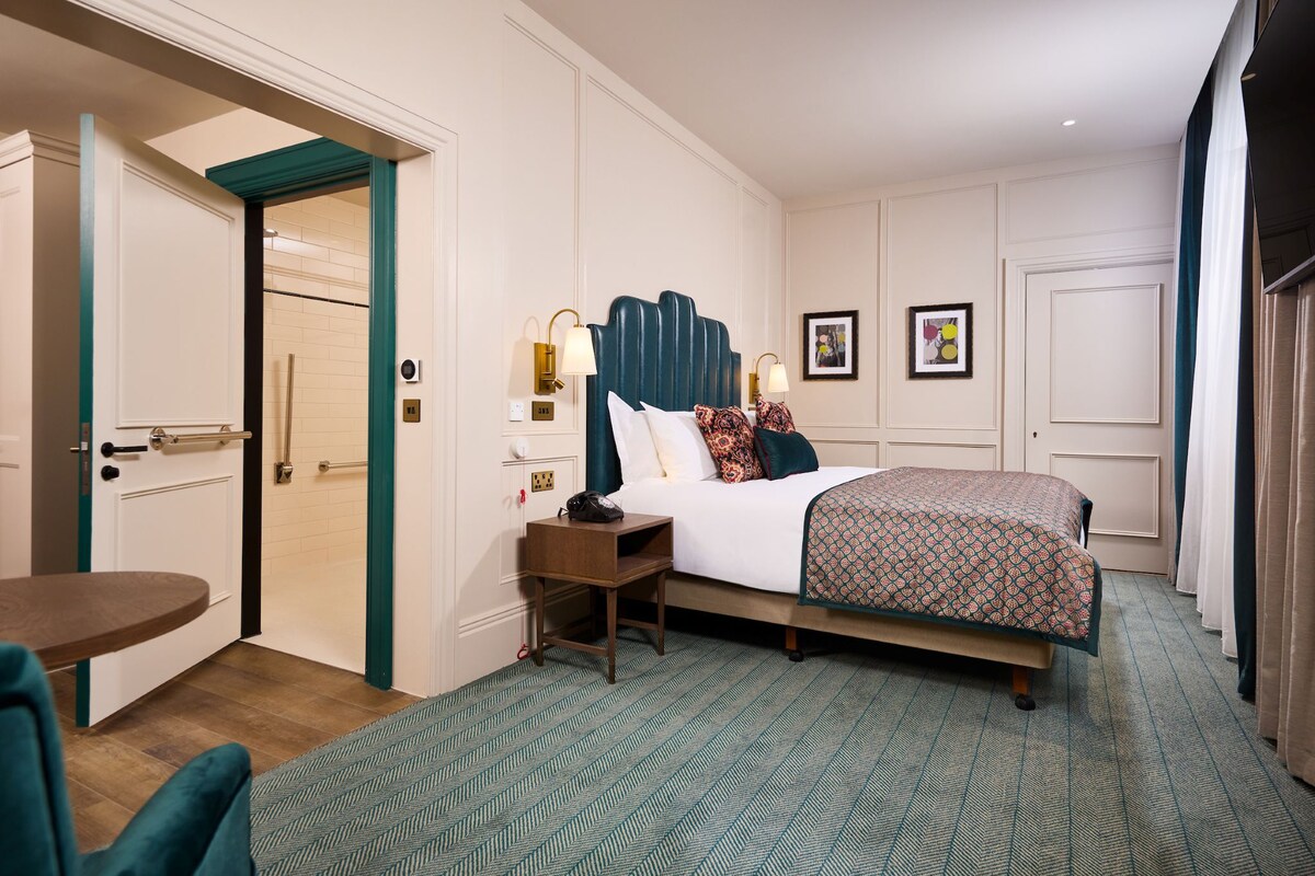 A hotel room with a bed, bedside table, and a chair.