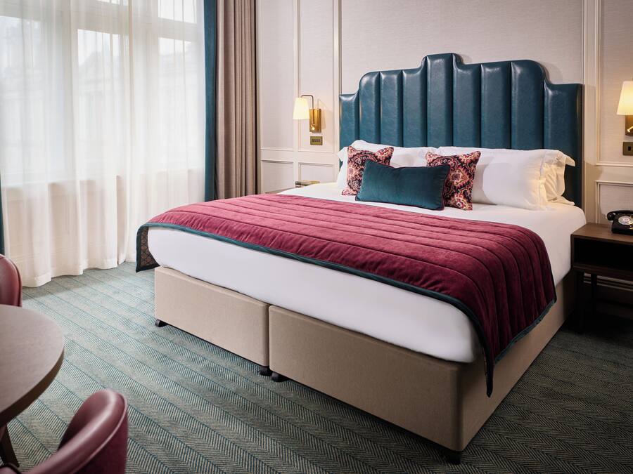 A hotel room with a large bed, a desk, and a chair.