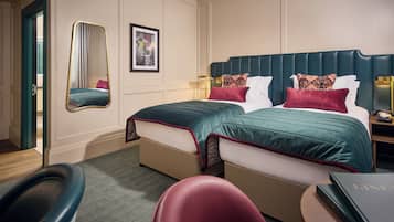 Una habitación de hotel con dos camas, un espejo, una mesita de noche con una lámpara y una silla.