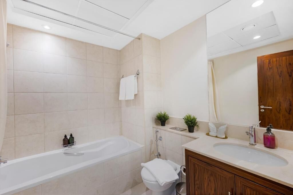 Un baño moderno con bañera, inodoro, lavabo y un espejo grande.