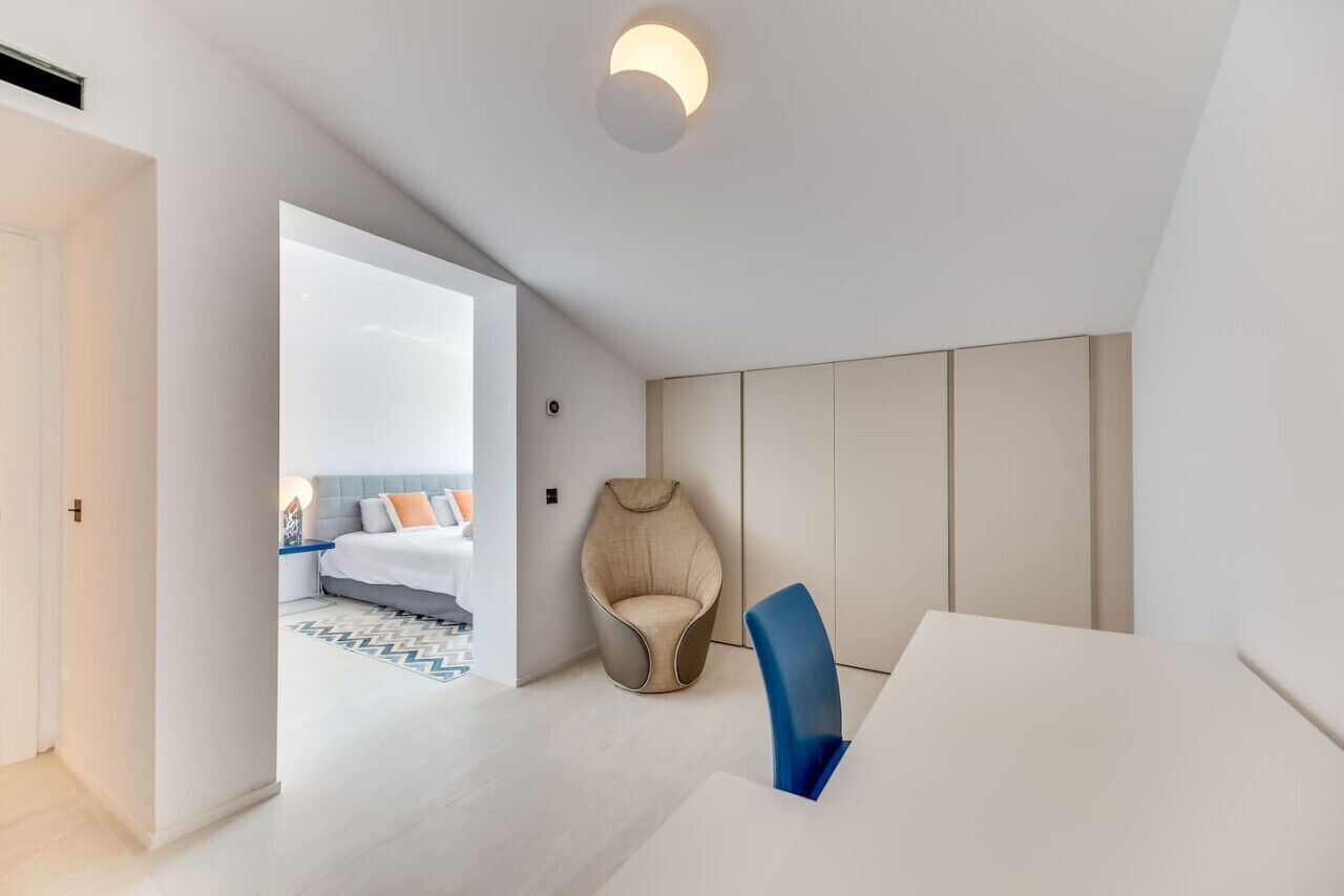Ett modernt hotellrum med en säng, en sittgrupp och utsikt in i ett annat rum.