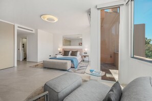 Une chambre d’hôtel moderne dotée d’un grand lit, d’un coin salon avec un canapé, d’une petite table et d’un balcon offrant une vue agréable.