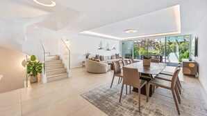 Ein modernes Interieur mit einer Treppe, einem Essbereich und einem großen Fenster mit Blick auf Grünflächen.