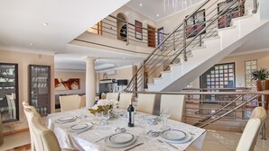 A dining area with a table set for six, a staircase, and a view of the upper floor. - Sunshine Villa in Vilamoura (Vilamoura)