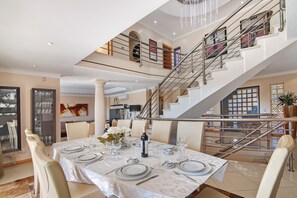 A dining area with a table set for six, a staircase, and a view of the upper floor. - Sunshine Villa in Vilamoura (Vilamoura)
