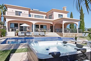 Una casa de dos plantas con piscina, jacuzzi y zona de estar al aire libre.