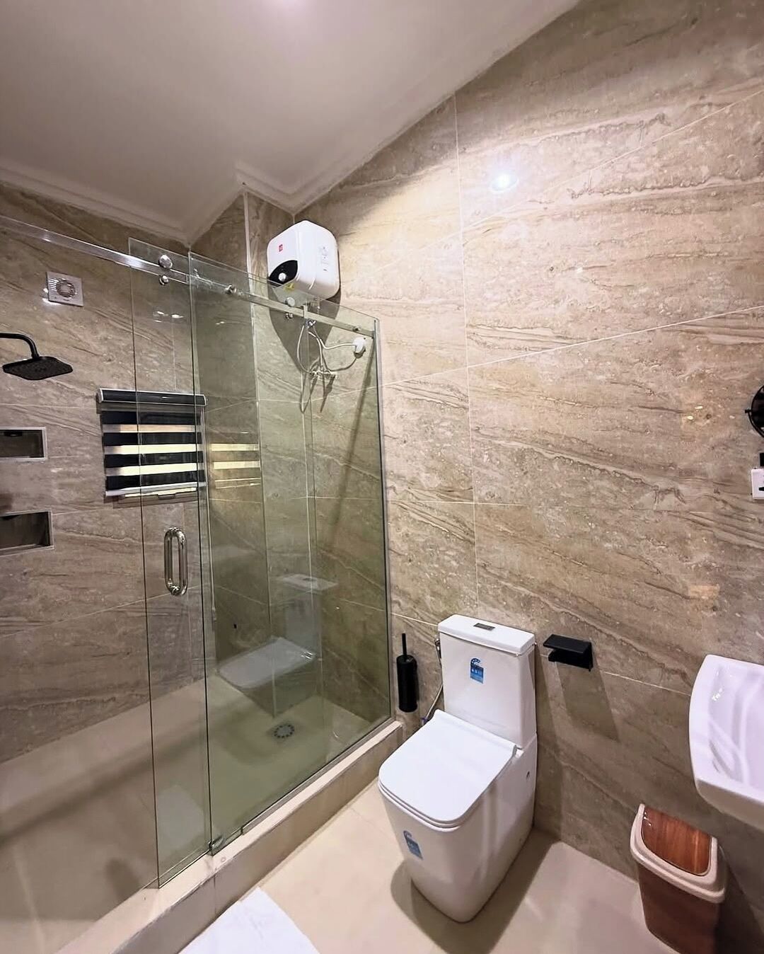 A modern bathroom with a glass-enclosed shower, a toilet, and a sink.