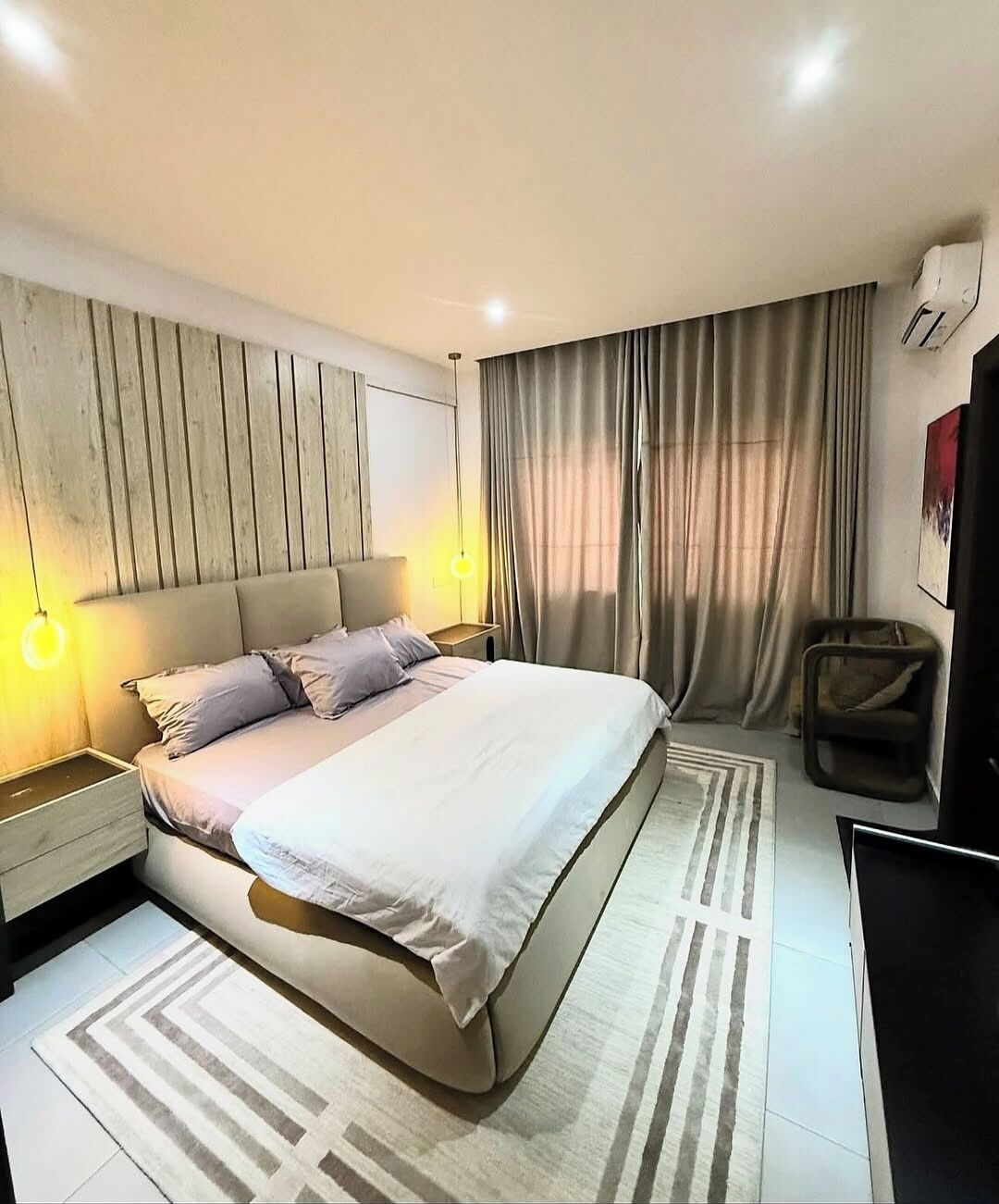 A modern hotel room with a large bed, bedside tables, a desk, and a chair.