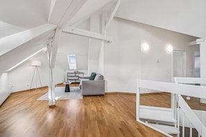 Un vaste appartement de style « loft » avec de hauts plafonds, des poutres apparentes et un plancher en bois.