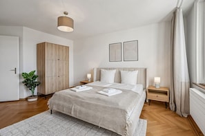 Une chambre moderne avec un grand lit, des tables de chevet, une armoire et un ventilateur de plafond.